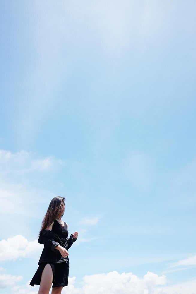 Asian woman long hair standing for freedom and happy in the wind with cloud in the sky. Happiness of life is successful and travel in the world. Copy Space photo