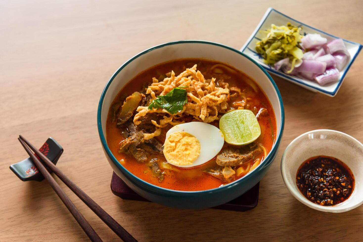 Northern Thai style curried noodle soup with beef and egg on wooden table photo