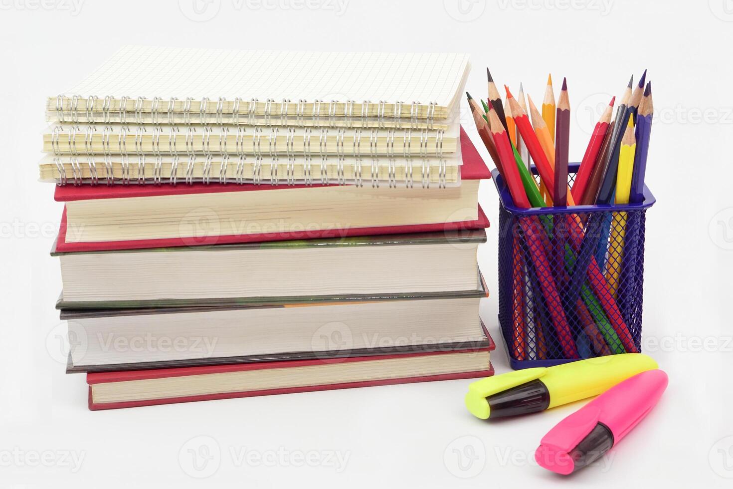 Crayon or colored pencils in box with side stack of books and school supplies on with background. Learning, study and office equipment concept. photo
