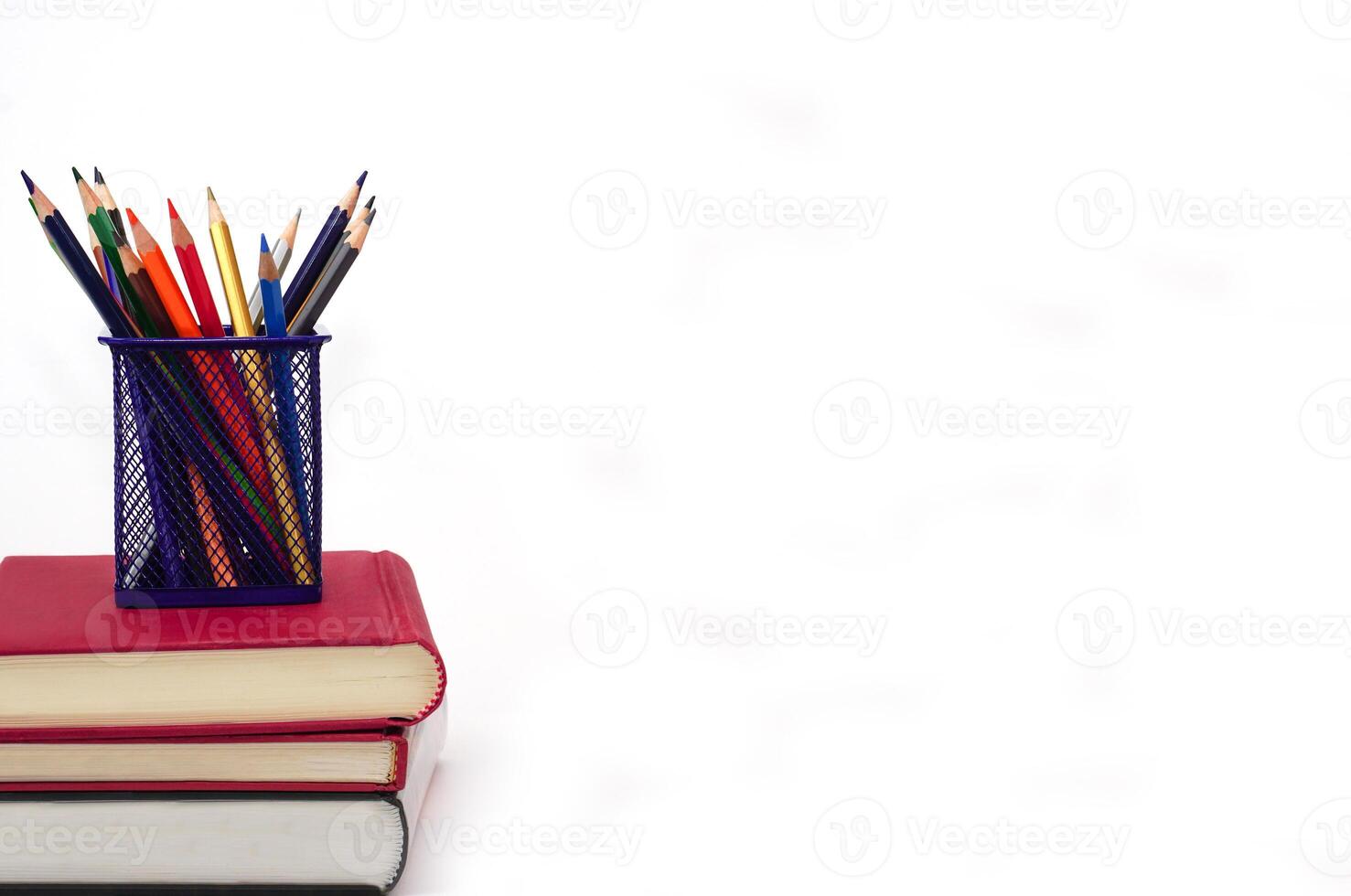 Crayon or colored pencils in box laying on a stack of books, white background. Knowledge and education concept. photo