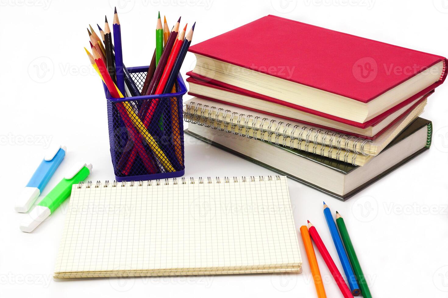 Crayon or colored pencils in box with side stack of books and school supplies on with background. Learning, study and office equipment concept. photo