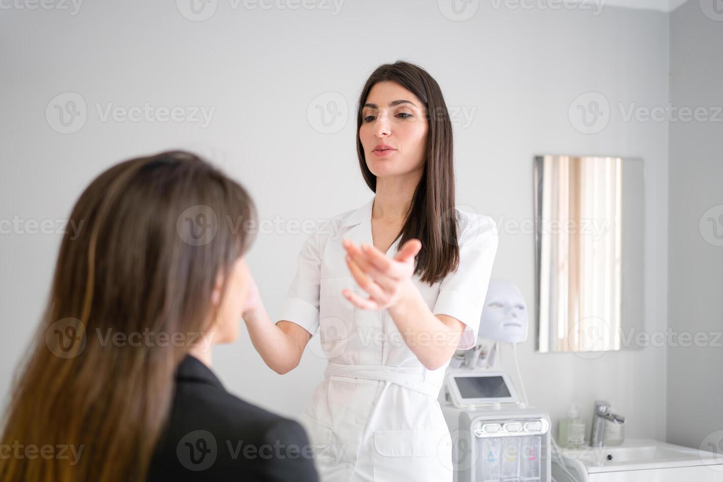 Female cosmetician preparing client for facelift injection in clinic photo