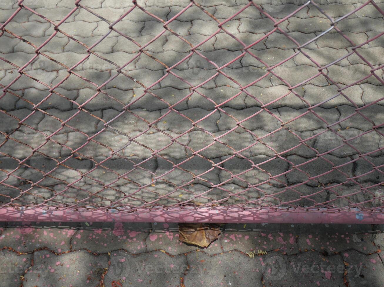 mesh wire fence has a cement floor and tree shadows in the background photo