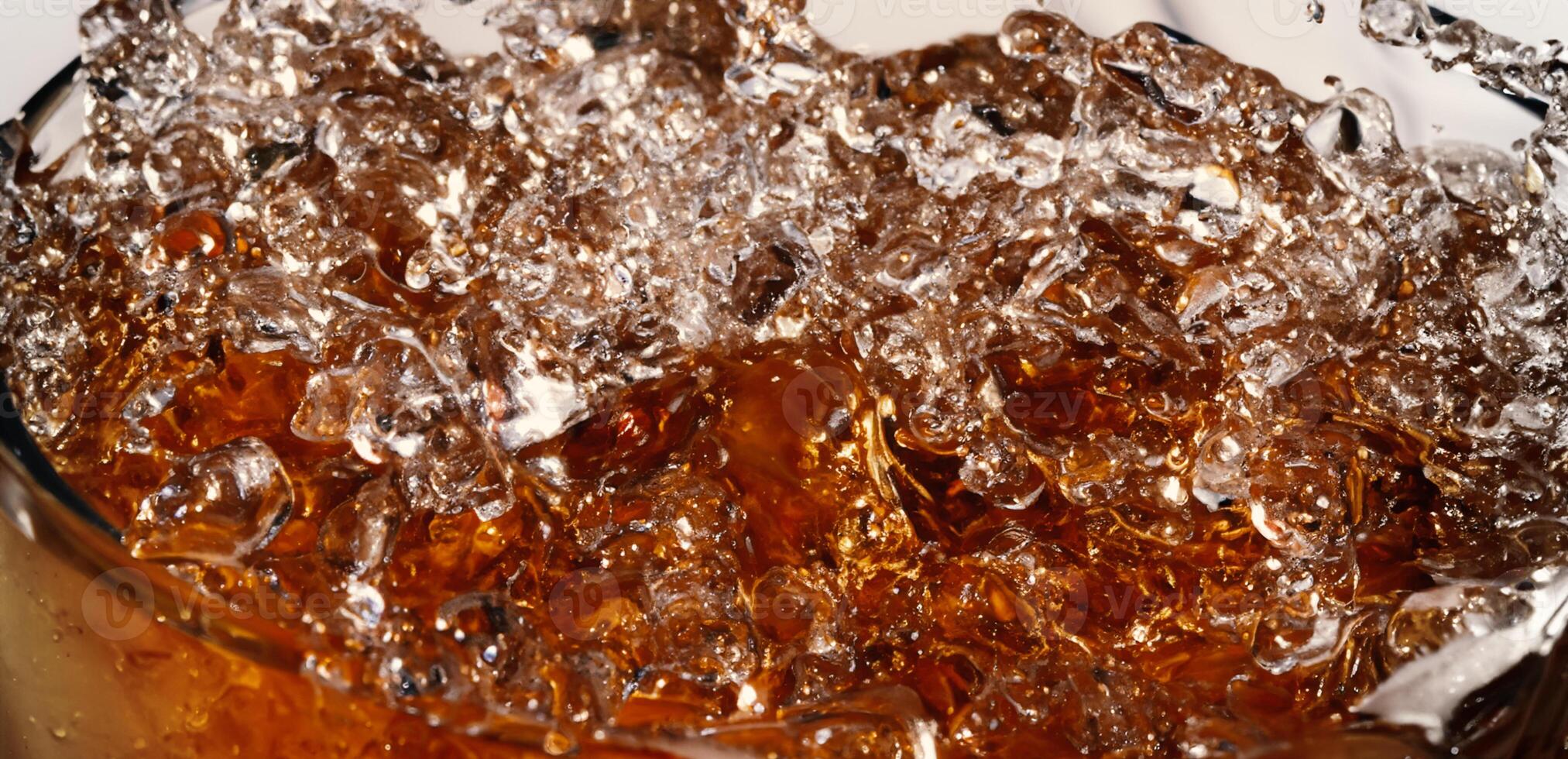 Splashing of Cola and Ice. Cola soda and ice splashing fizzing or floating up to top of surface. Close up of ice in cola water. Texture of carbonate drink with bubbles in glass. Cold drink background photo