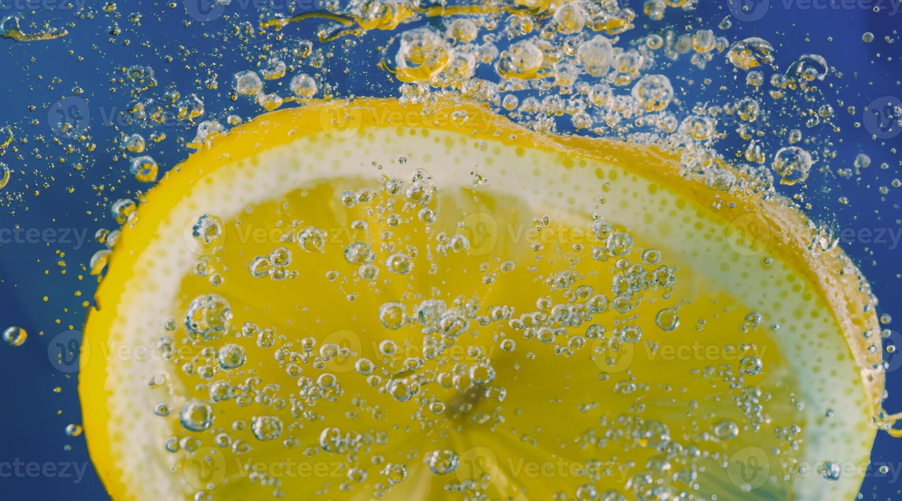 Underwater lemon slice in soda water or lemonade with bubbles. photo