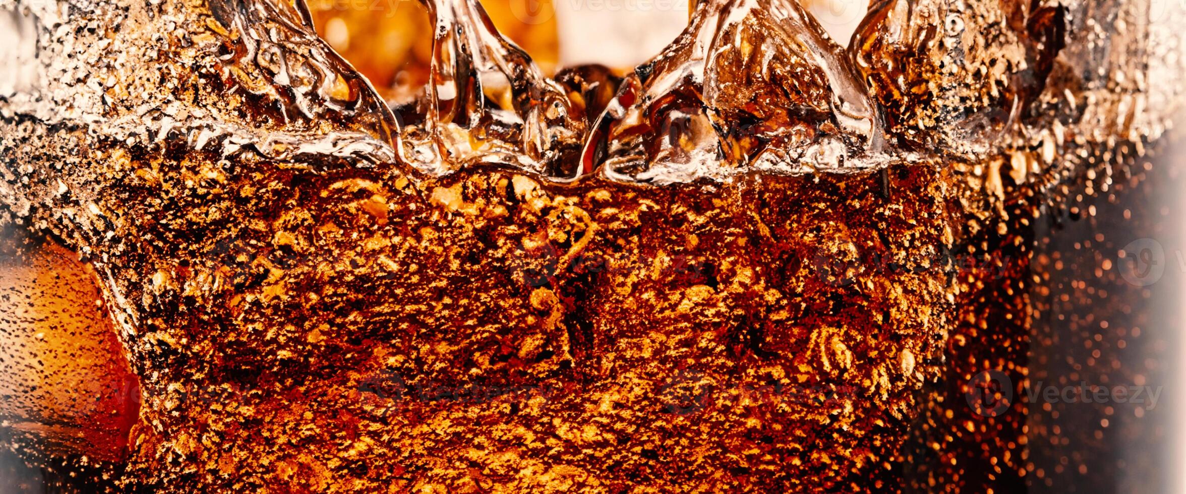 Splashing of Cola and Ice. Cola soda and ice splashing fizzing or floating up to top of surface. Close up of ice in cola water. Texture of carbonate drink with bubbles in glass. Cold drink background photo