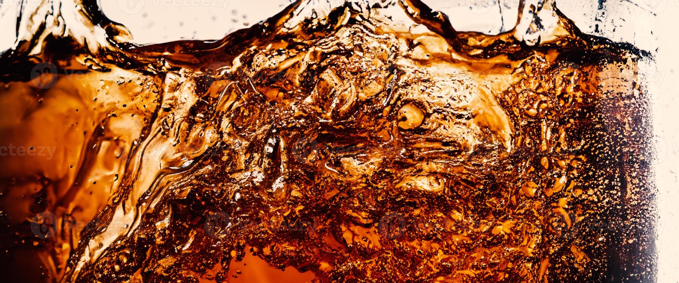 Splashing of Cola and Ice. Cola soda and ice splashing fizzing or floating up to top of surface. Close up of ice in cola water. Texture of carbonate drink with bubbles in glass. Cold drink background photo