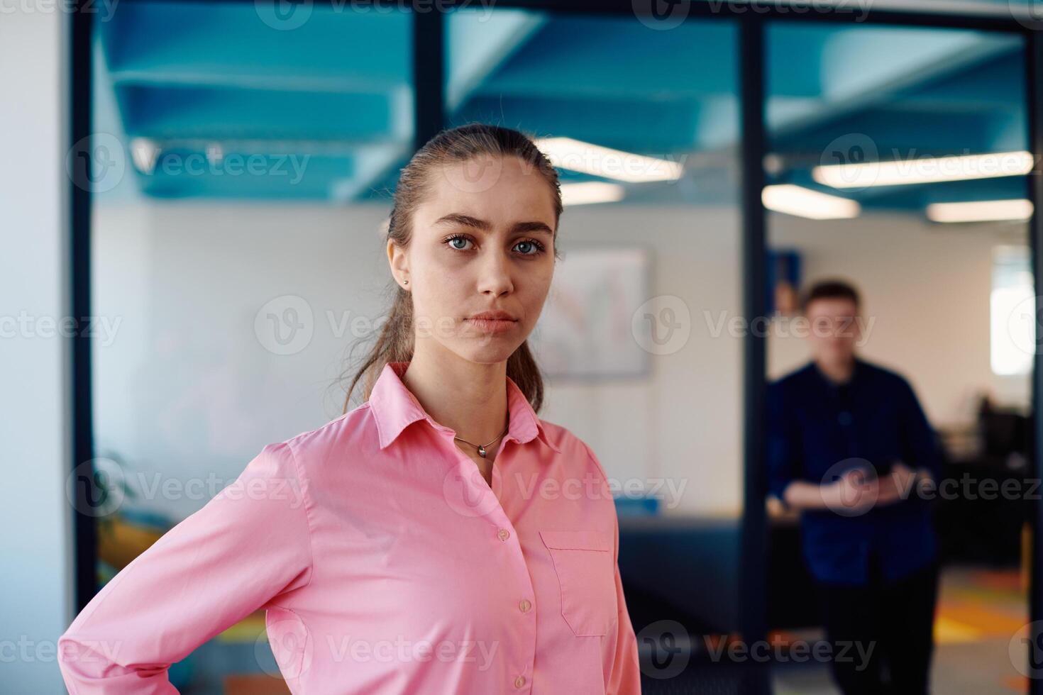 Portrait of young smiling business woman in creative open space coworking startup office. Successful businesswoman standing in office with copyspace. Coworkers working in background photo