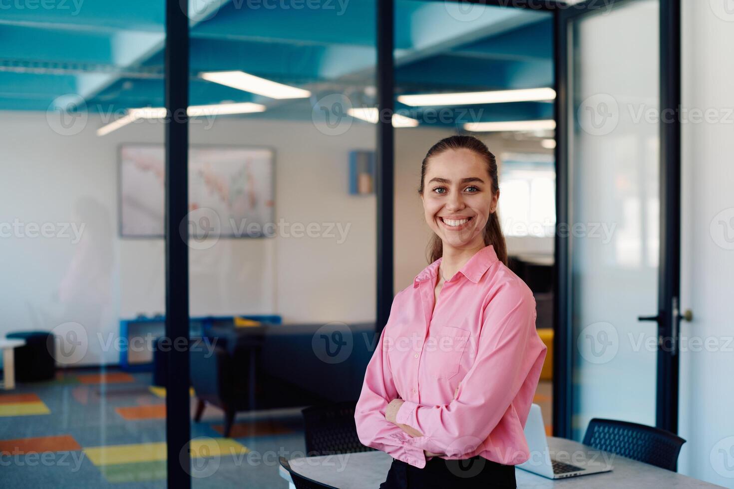 Portrait of a business woman in a creative open space coworking startup office with crossed arms. Successful businesswoman standing in office with copyspace. Associates work in the background photo