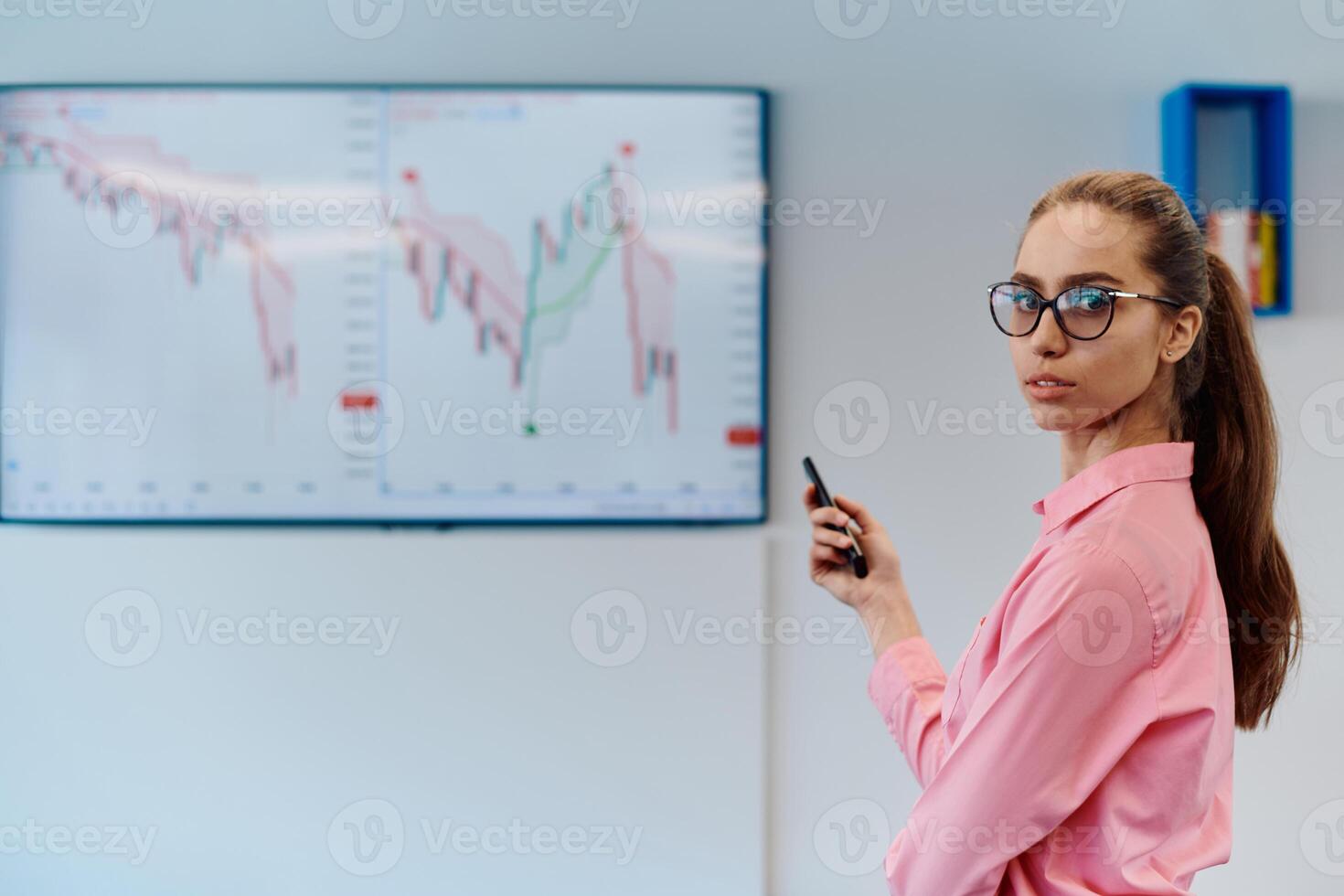 On Stage, Successful Female Speaker Presents Technological Product, Uses Remote Control for Presentation, Showing Infographics, Statistics Animation on Screen. Live Event Device Release photo