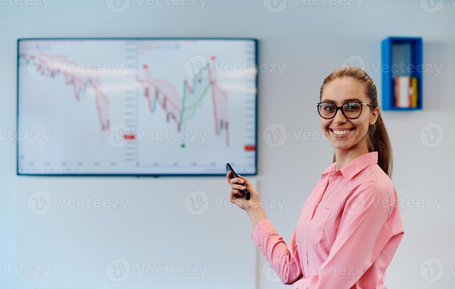 On Stage, Successful Female Speaker Presents Technological Product, Uses Remote Control for Presentation, Showing Infographics, Statistics Animation on Screen. Live Event Device Release photo