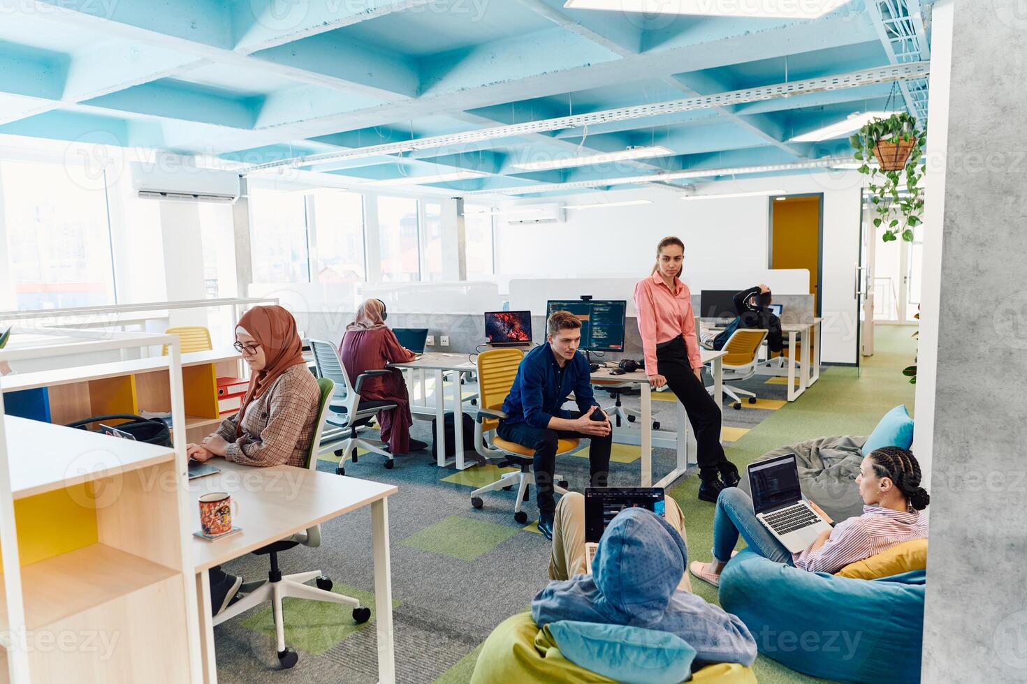 In a modern startup office, a diverse group of young and capable businesspeople engage in lively discussions about various projects, showcasing teamwork, innovation, and entrepreneurial spirit photo