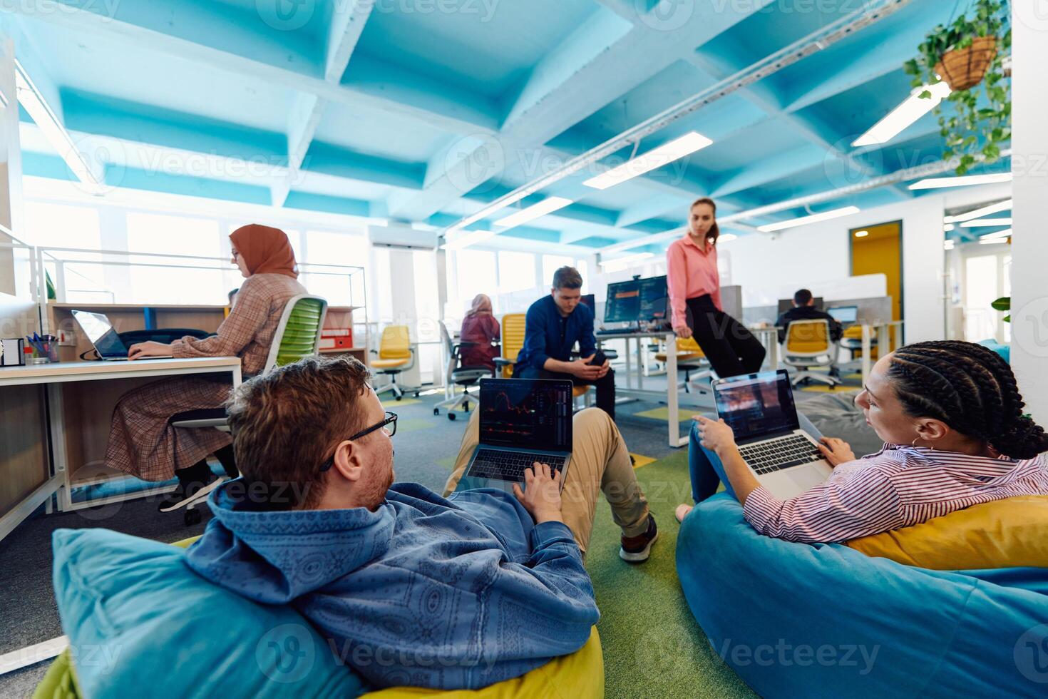 In a modern startup office, a diverse group of young and capable businesspeople engage in lively discussions about various projects, showcasing teamwork, innovation, and entrepreneurial spirit photo