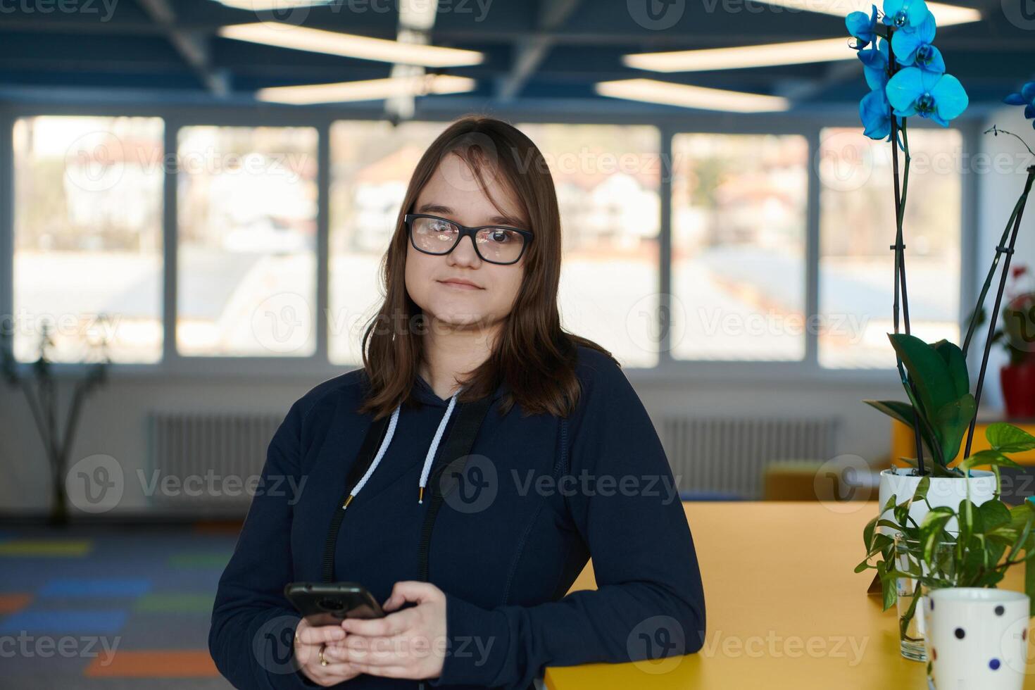 Portrait of happy multiethnic businesswoman using smartphone in agency. Successful business woman in casual clothing working in coworking creative open space office photo