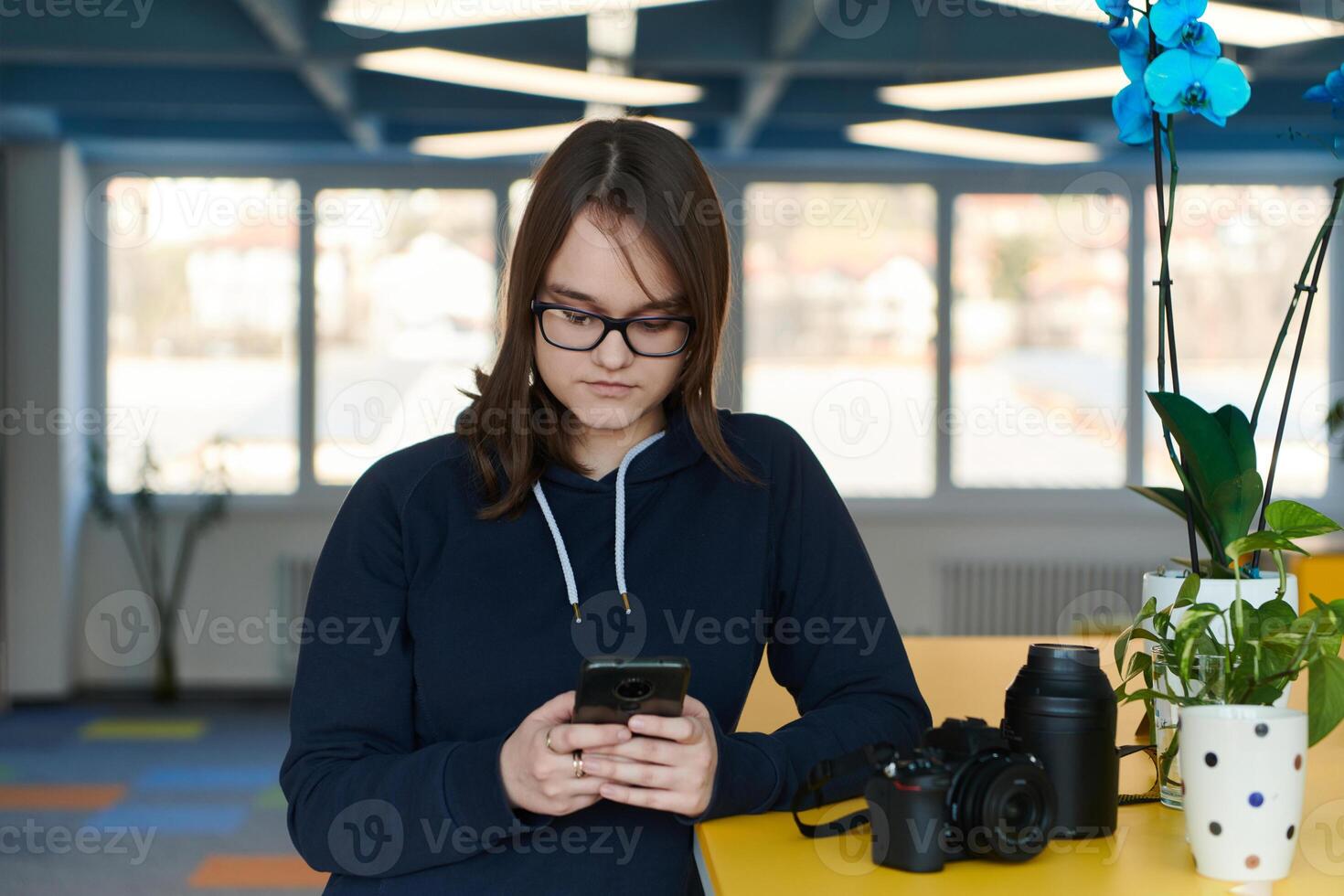 Portrait of happy multiethnic businesswoman using smartphone in agency. Successful business woman in casual clothing working in coworking creative open space office photo
