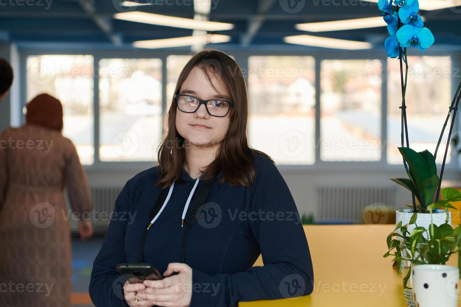 Portrait of happy multiethnic businesswoman using smartphone in agency. Successful business woman in casual clothing working in coworking creative open space office photo