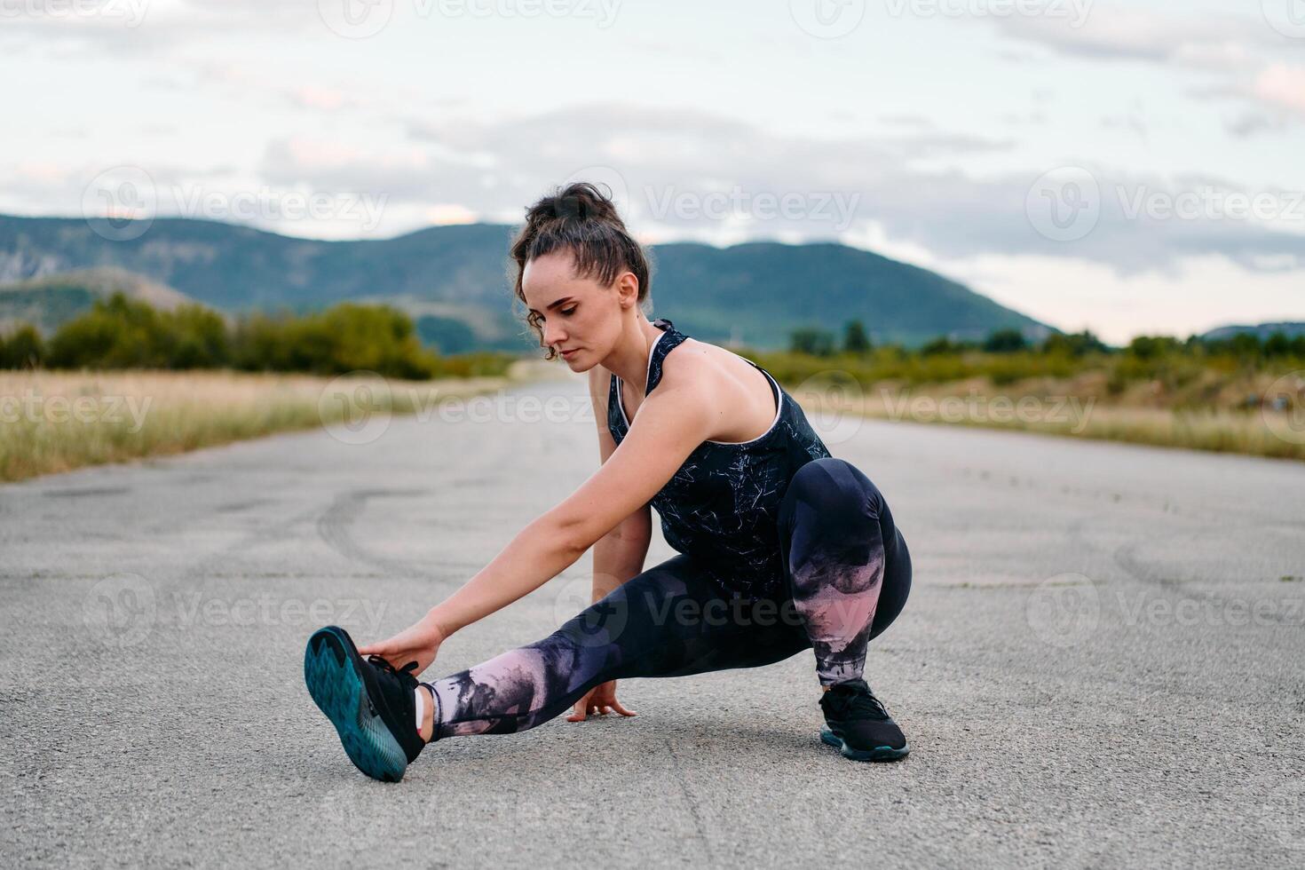 Determined Female Athlete Stretching After an Intense Run Through Rugged Mountain Terrain. photo