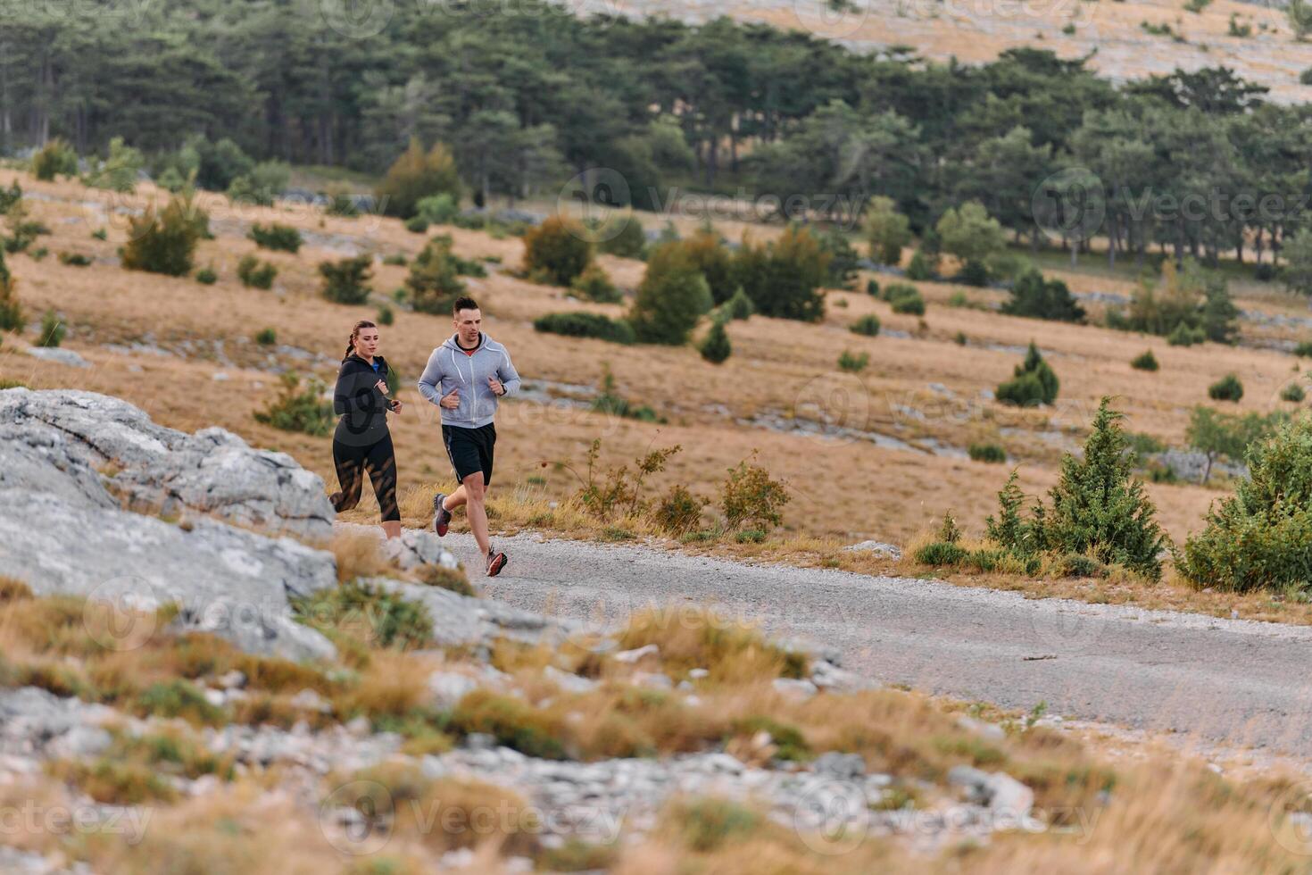 A couple dressed in sportswear runs along a scenic road during an early morning workout, enjoying the fresh air and maintaining a healthy lifestyle photo