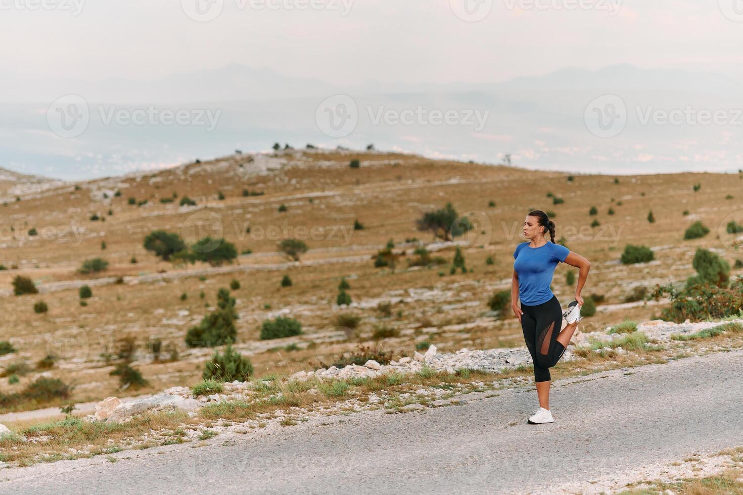 Determined Female Athlete Stretching After an Intense Run Through Rugged Mountain Terrain. photo