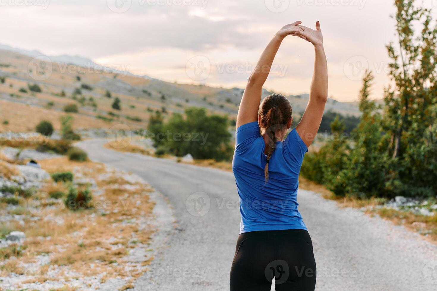 Determined Female Athlete Stretching After an Intense Run Through Rugged Mountain Terrain. photo