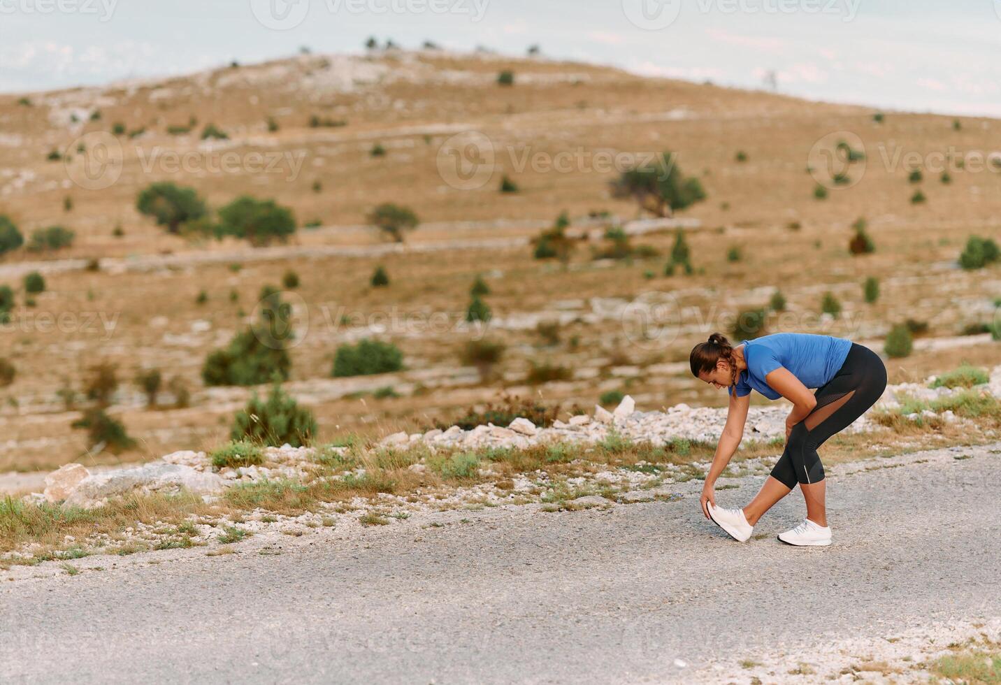 Determined Female Athlete Stretching After an Intense Run Through Rugged Mountain Terrain. photo
