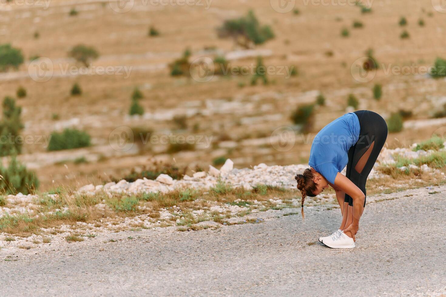 Determined Female Athlete Stretching After an Intense Run Through Rugged Mountain Terrain. photo