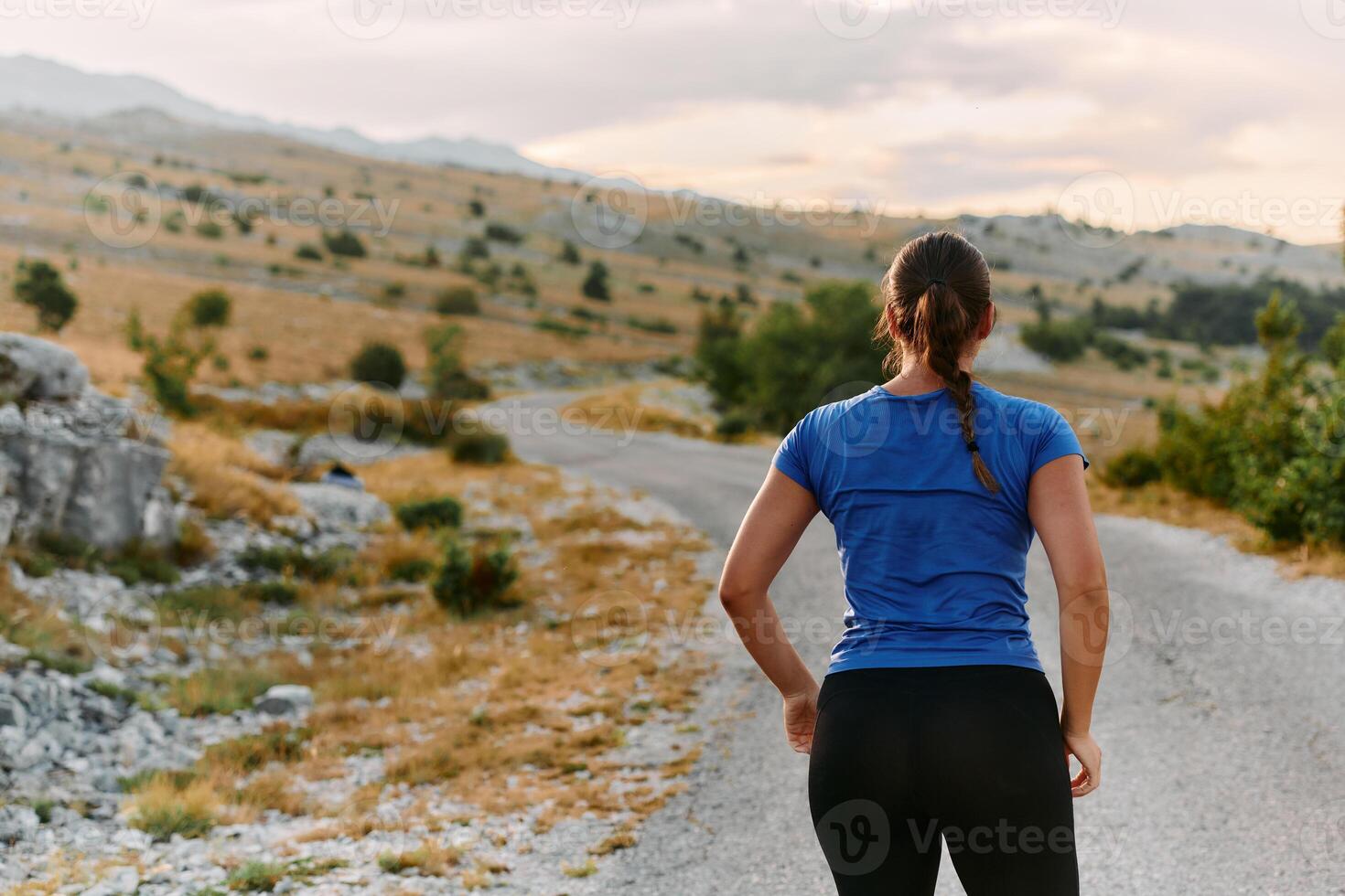 Determined Female Athlete Stretching After an Intense Run Through Rugged Mountain Terrain. photo
