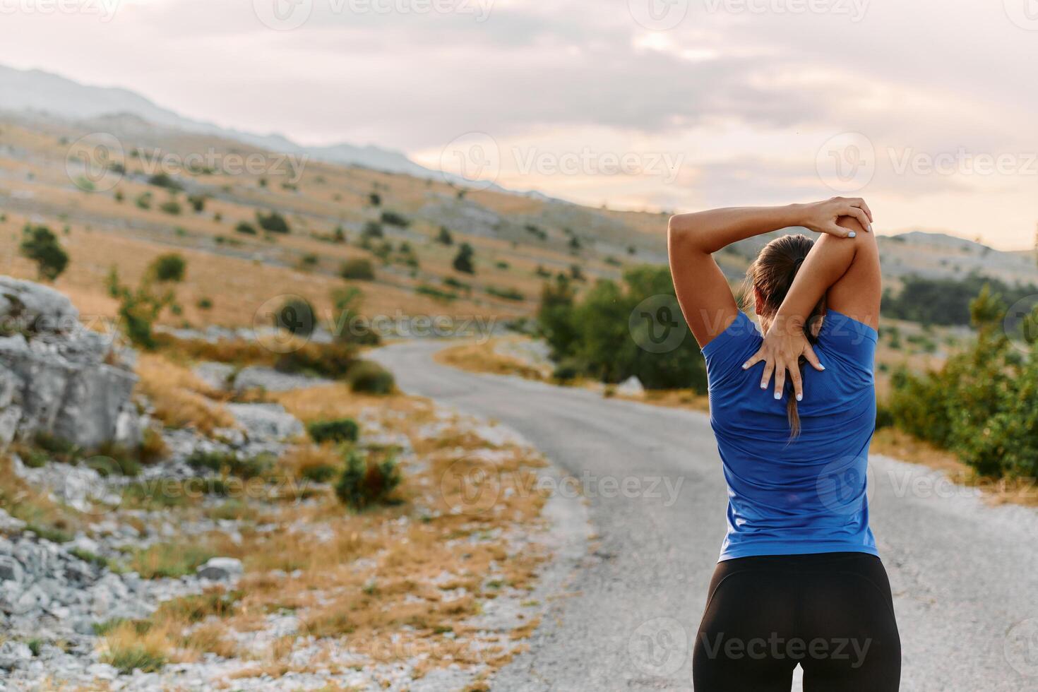 Determined Female Athlete Stretching After an Intense Run Through Rugged Mountain Terrain. photo