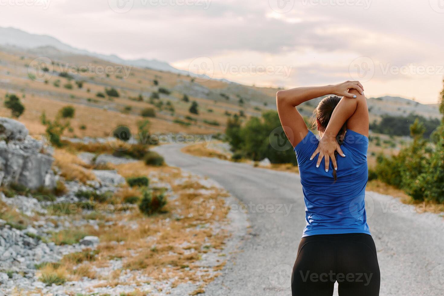 Determined Female Athlete Stretching After an Intense Run Through Rugged Mountain Terrain. photo