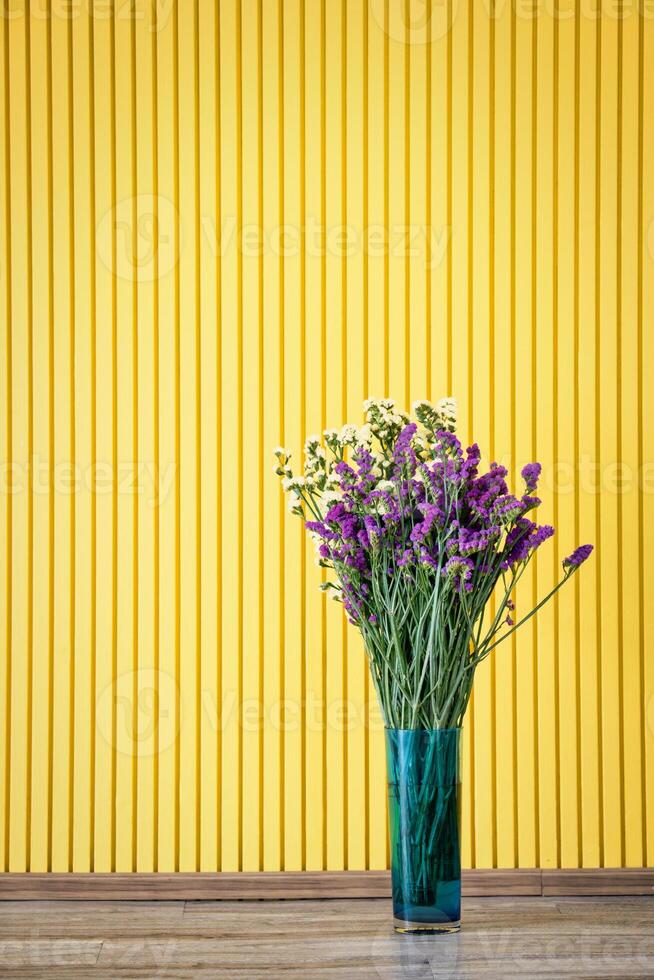 Yellow and purple flower in pot on yellow background. photo