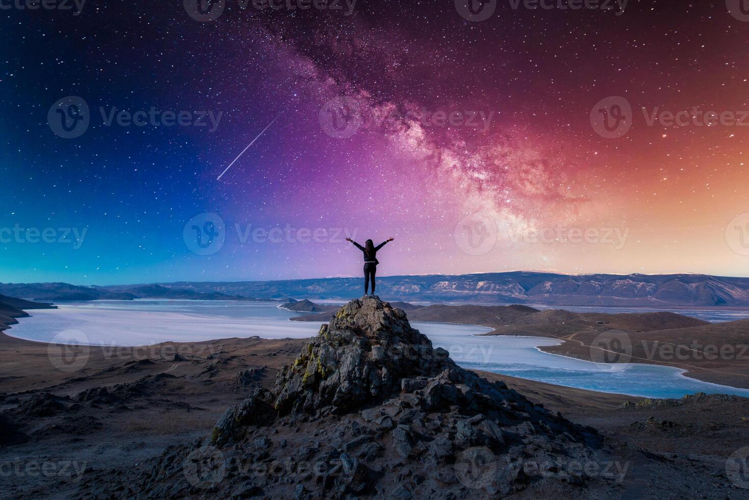 Traveler woman raising arm standing on mountain at with milky way in Lake Baikal, Siberia, Russia. photo