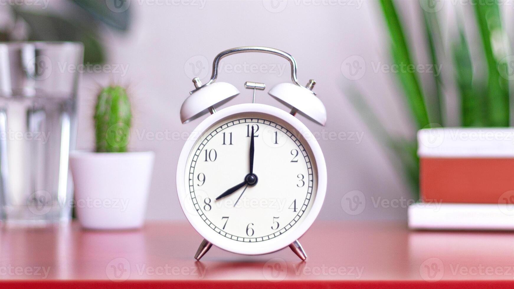 Classic white clock on a table. The clock hand points to 8 or 20. close up photo