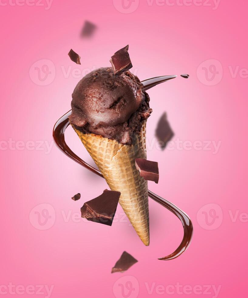Composition levitation of chocolate ice cream waffle cone with pieces of chocolate on pink background. In the air, vertical photo