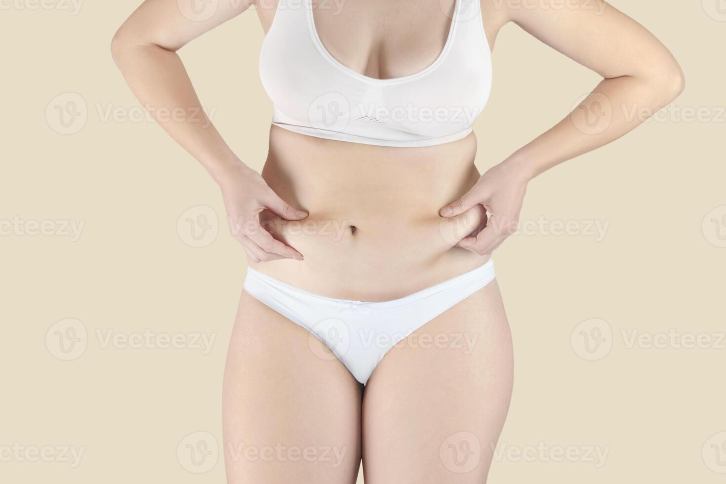 Woman has excess fat. Girl in underwear shows belly fat. She wants to lose weight nude yellow background photo