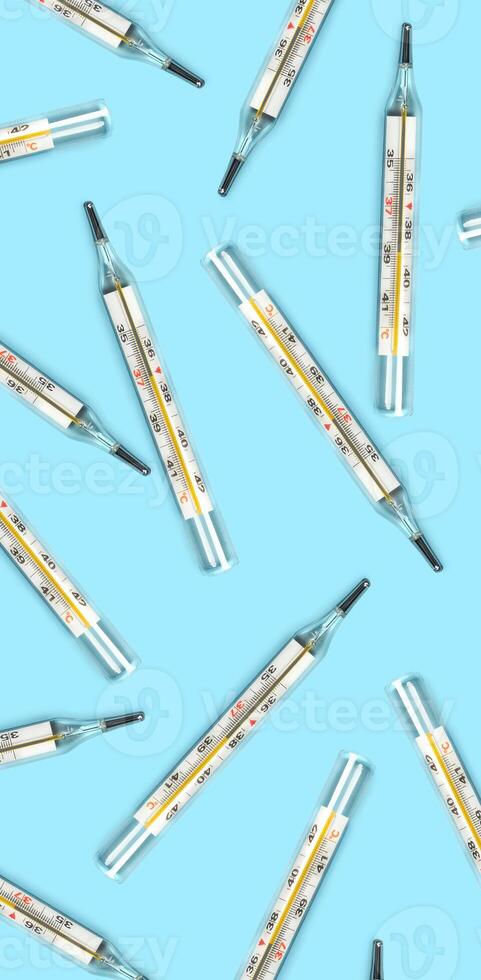 Mercury-in-glass thermometer creative pattern on blue background flat lay healthcare, treatment concept vertical photo