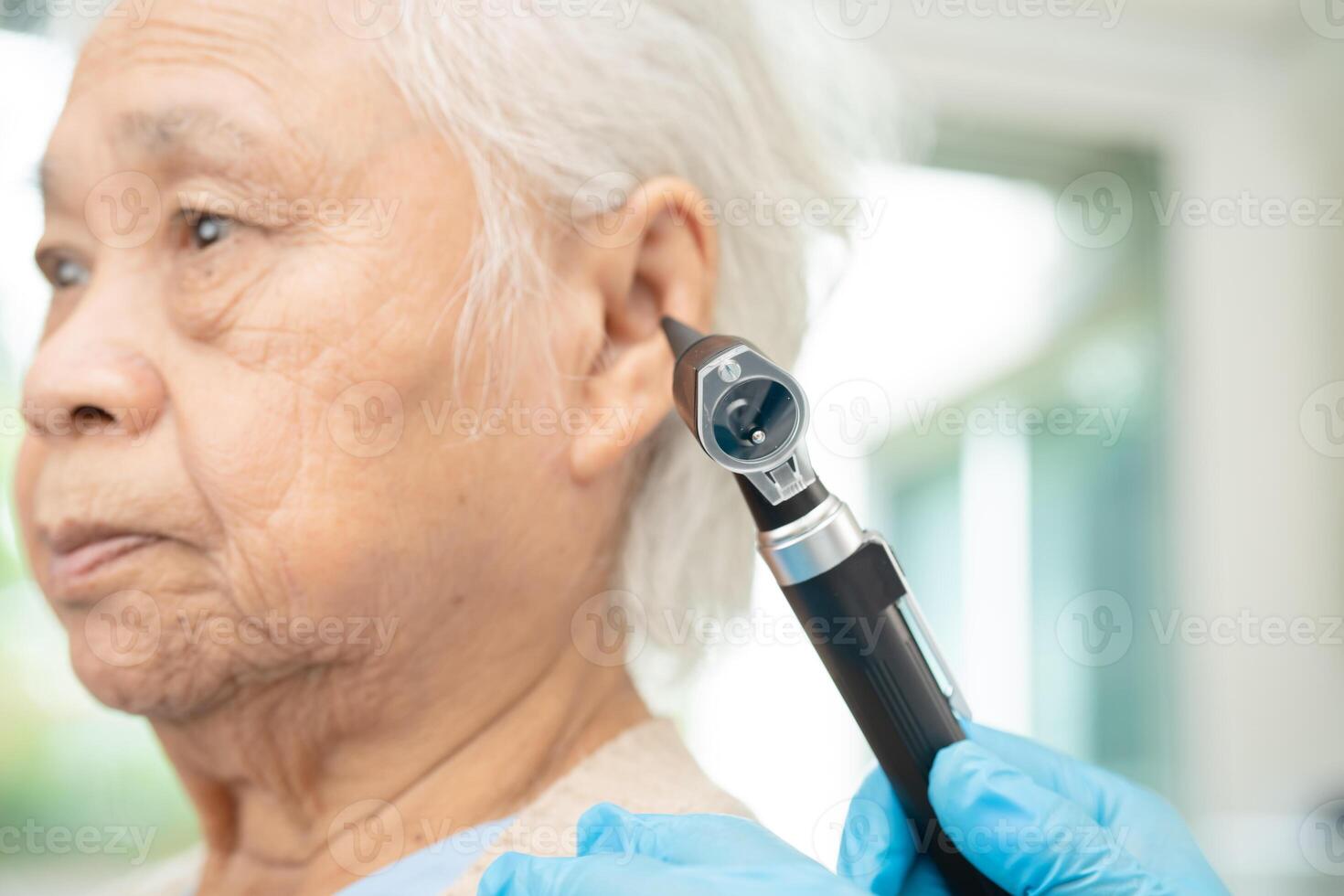 Audiologist or ENT doctor use otoscope checking ear of asian senior woman patient treating hearing loss problem. photo