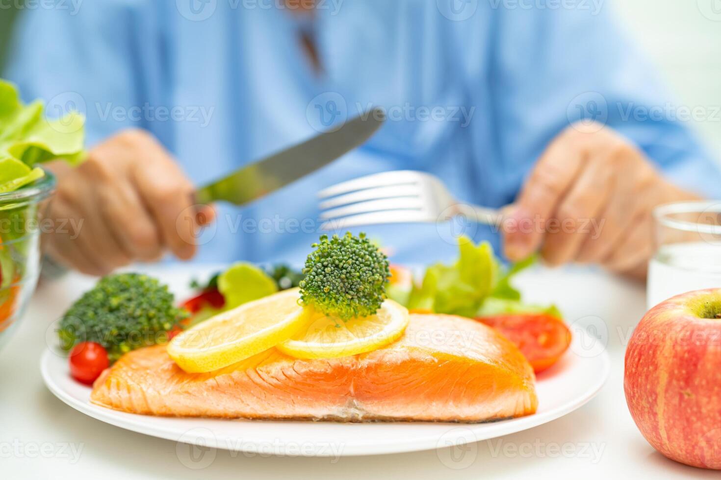 Asian elderly woman patient eating salmon steak breakfast with vegetable healthy food in hospital. photo