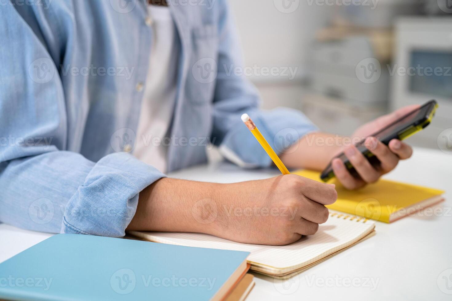 Teenage write in notebook and use mobile phone search data online to online learning university education. photo