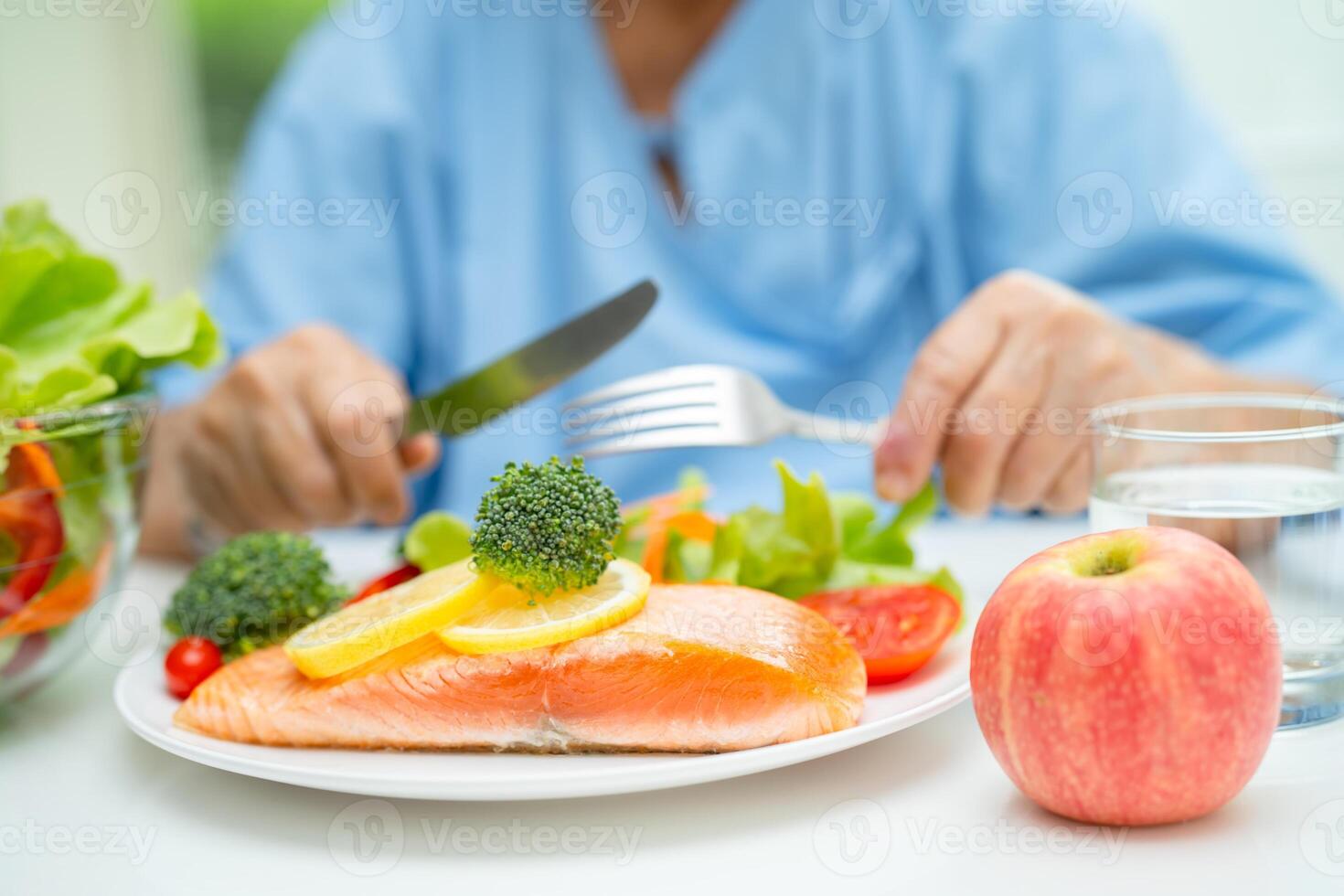 Asian elderly woman patient eating salmon steak breakfast with vegetable healthy food in hospital. photo