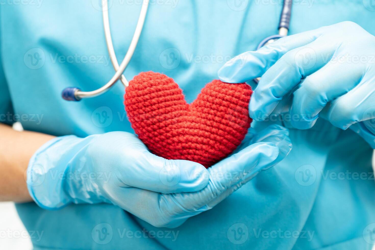 Doctor holding a red heart in hospital ward, healthy strong medical concept. photo