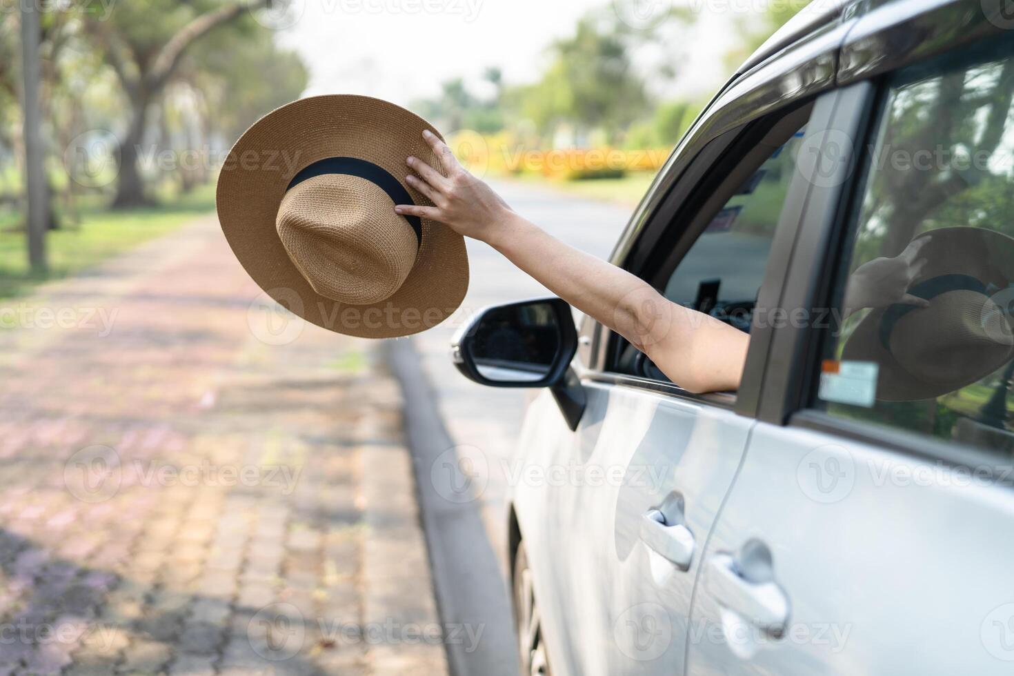 Happy enjoy and freedom in traveling trip with raised hand and holding hat outside of window car in summer vacation holiday. photo