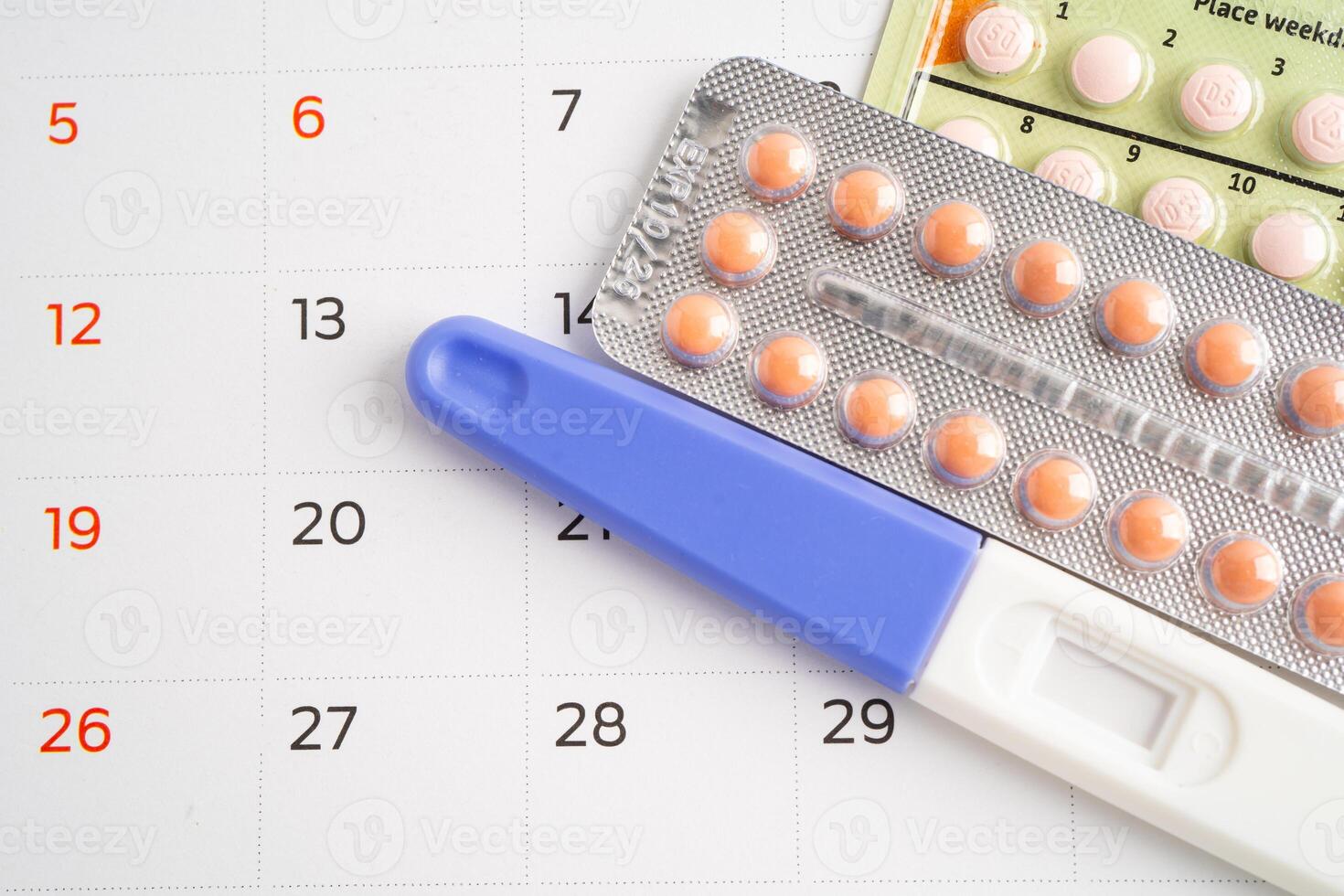 Pregnancy test and birth control pills on calendar, contraception health and medicine. photo