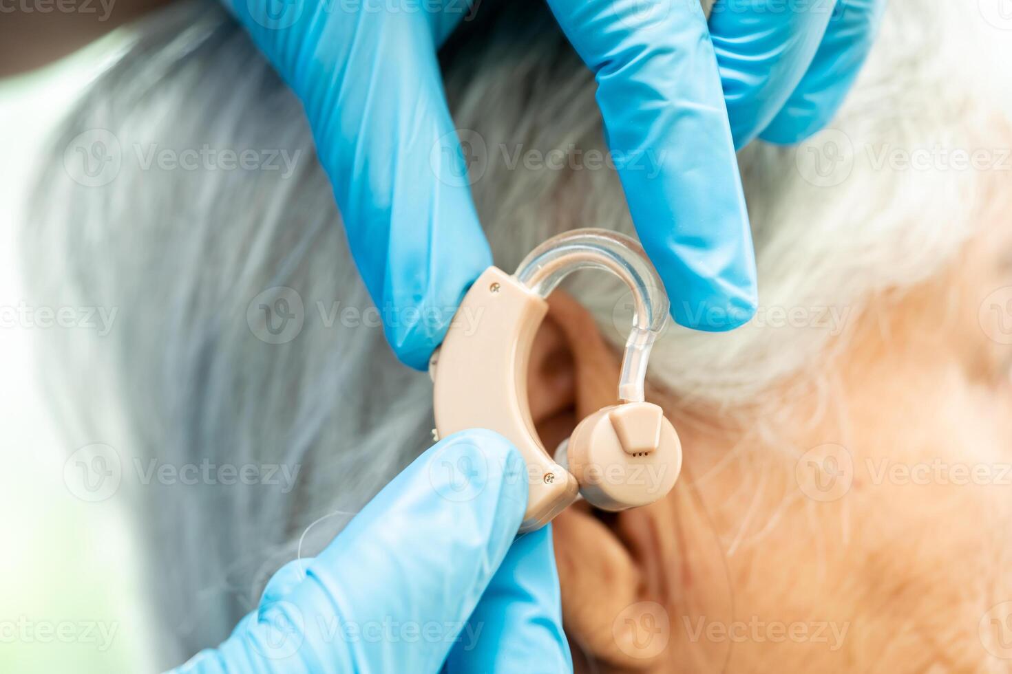 Asian senior woman patient wearing a hearing aid for treating hearing loss problem. photo