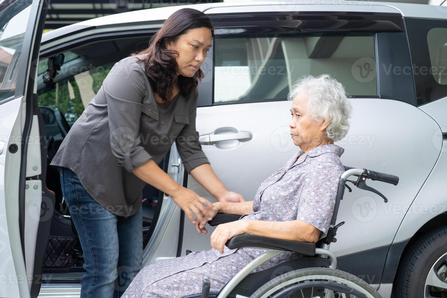 Caregiver help and support asian elderly woman sitting on wheelchair prepare get to her car to travel in holiday. photo