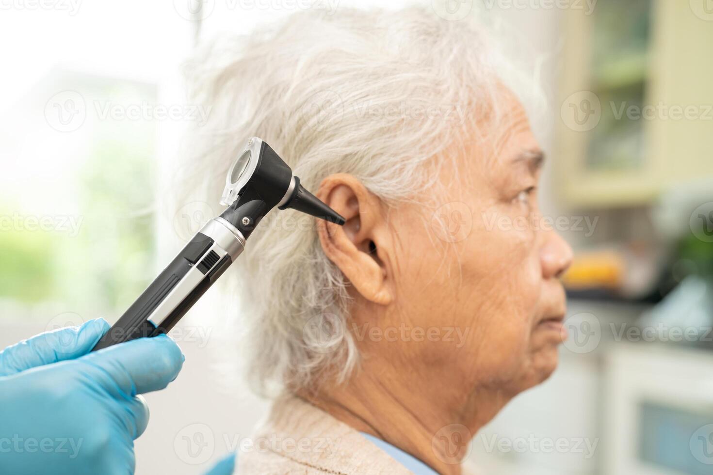 Audiologist or ENT doctor use otoscope checking ear of asian senior woman patient treating hearing loss problem. photo