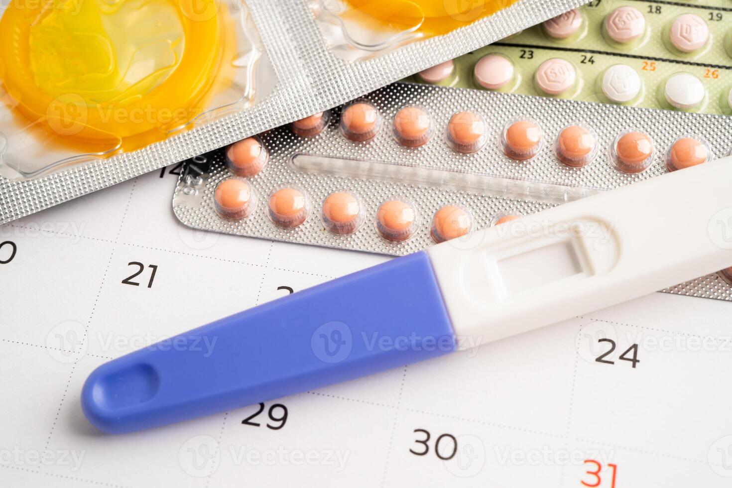 Pregnancy test and birth control pills on calendar, contraception health and medicine. photo