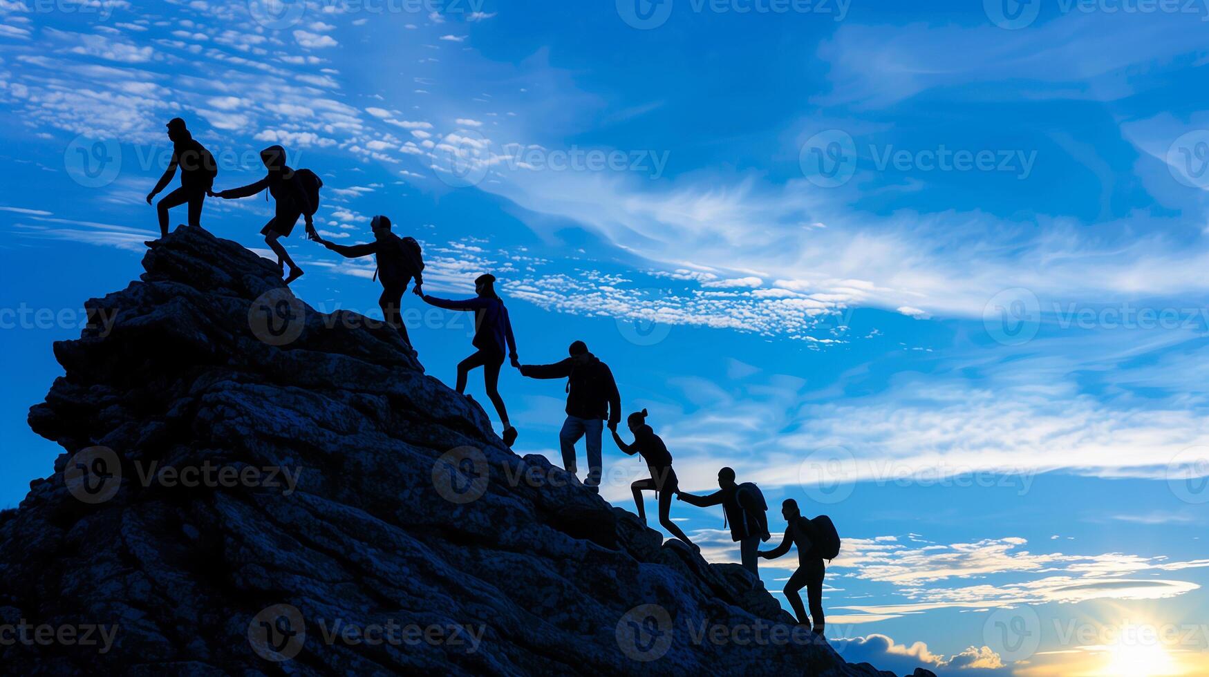 Silhouette success teamwork hold hand tightly and help each other climbing to top of mountain for goal. photo
