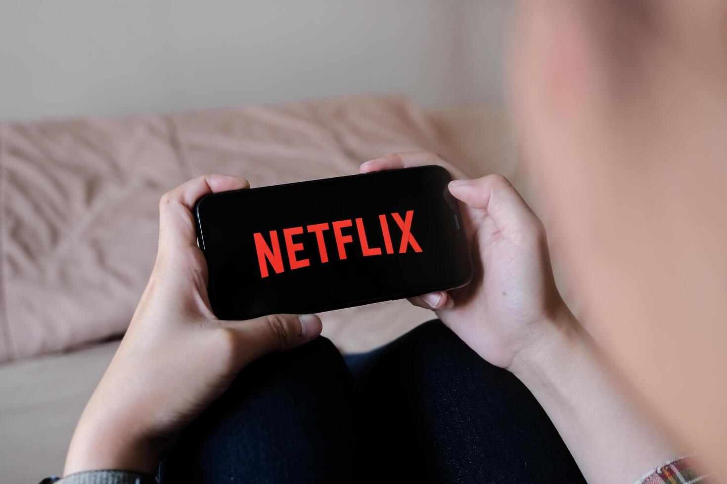 CHIANG MAI, THAILAND, MAR 29, 2020. Woman hand holding Smart Phone with Netflix logo on Apple iPhone Xs at home. photo