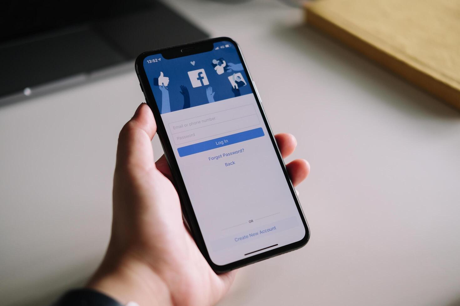 CHIANG MAI ,THAILAND - JULY 3, 2020 . Woman hand holding iPhone X to use facebook with login screen.Facebook is a largest social network and most popular social networking site in the world photo