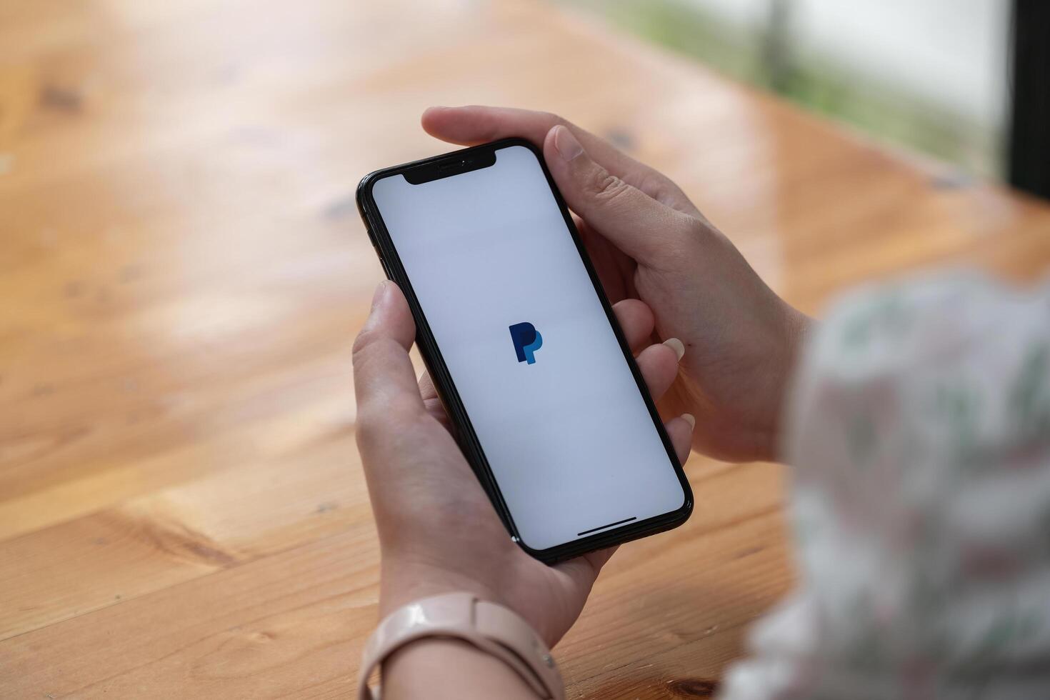 CHIANG MAI, THAILAND - NOV 14, 2021 . Woman hands holding iPhone X with PayPal apps on the screen. PayPal is an online electronic payment system photo